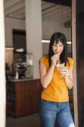 Happy mature woman drinking juice in cafe doorway - JOSEF20411