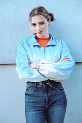 Confident woman standing with arms crossed in front of wall - YHF00057