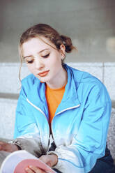 Frau mit blauer Jacke liest ein Buch - YHF00061