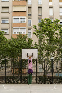 Paar spielt Basketball im Hof in der Nähe des Gebäudes - AFVF09289