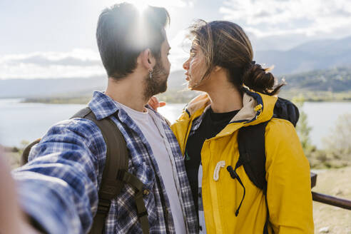 Man taking selfie with woman on sunny day - JJF00979