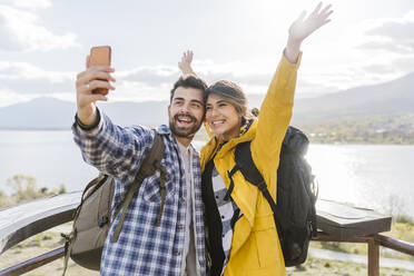 Cheerful couple taking selfie standing at observation point - JJF00981
