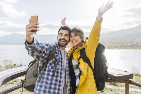 Cheerful couple taking selfie standing at observation point - JJF00981