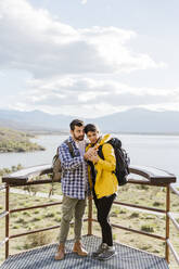 Touristenpaar, das sich ein Smartphone teilt, steht am Aussichtspunkt - JJF00984