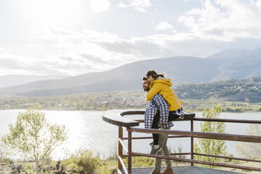 Man piggybacking girlfriend standing on observation point - JJF00988