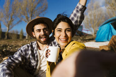 Happy woman holding mug and taking selfie with man - JJF01006