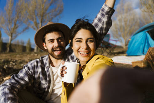 Happy woman holding mug and taking selfie with man - JJF01006