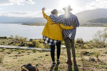 Man and woman standing with arms around in front of lake - JJF01011