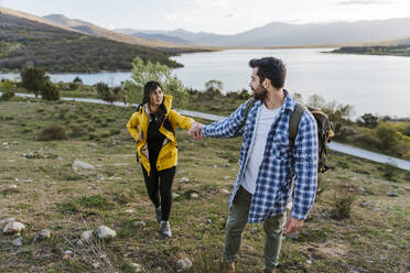 Boyfriend holding hand of girlfriend standing on mountain - JJF01036