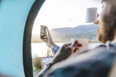 Boyfriend taking selfie with girlfriend having coffee in tent - JJF01042
