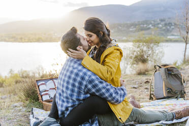 Romantic couple sitting on picnic blanket in front of mountain - JJF01044