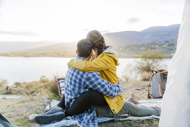 Couple looking at mountains sitting near tent - JJF01046