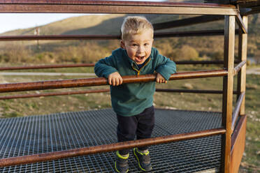 Cheerful boy screaming at railing - JJF01052