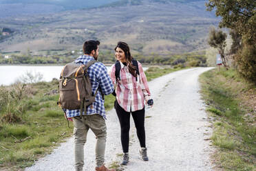 Couple wearing backpacks standing on footpath - JJF01071