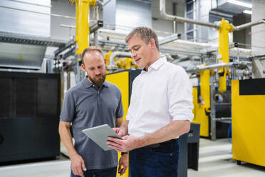 Employee and businessman with digital tablet talking in factory - DIGF20101