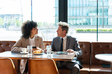 Senior businessman and beautiful hispanic businesswoman meeting in a bar restaurant - Two colleagues bonding in a cafe after work - DMDF00583