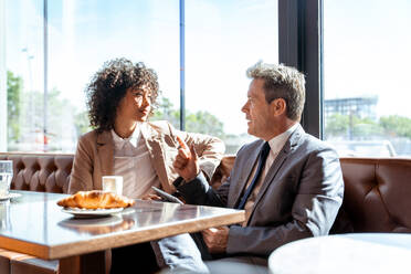 Senior businessman and beautiful hispanic businesswoman meeting in a bar restaurant - Two colleagues bonding in a cafe after work - DMDF00585