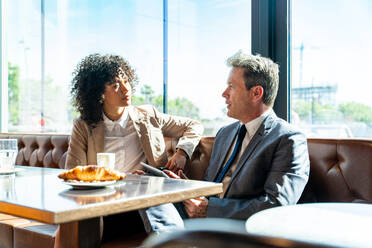 Senior businessman and beautiful hispanic businesswoman meeting in a bar restaurant - Two colleagues bonding in a cafe after work - DMDF00586