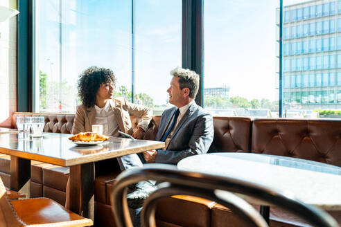 Senior businessman and beautiful hispanic businesswoman meeting in a bar restaurant - Two colleagues bonding in a cafe after work - DMDF00587