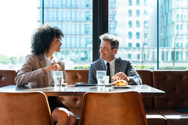 Senior businessman and beautiful hispanic businesswoman meeting in a bar restaurant - Two colleagues bonding in a cafe after work - DMDF00589