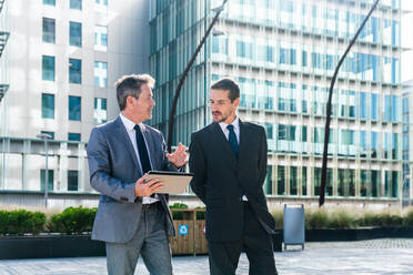 Multiracial group of business people bonding outdoors - International business corporate team wearing elegant suit meeting in a business park - DMDF00605