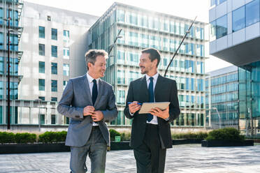 Multiracial group of business people bonding outdoors - International business corporate team wearing elegant suit meeting in a business park - DMDF00606