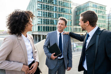 Multiracial group of business people bonding outdoors - International business corporate team wearing elegant suit meeting in a business park - DMDF00612