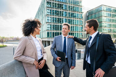 Multiracial group of business people bonding outdoors - International business corporate team wearing elegant suit meeting in a business park - DMDF00613