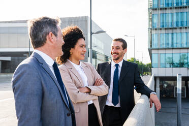 Multiracial group of business people bonding outdoors - International business corporate team wearing elegant suit meeting in a business park - DMDF00629