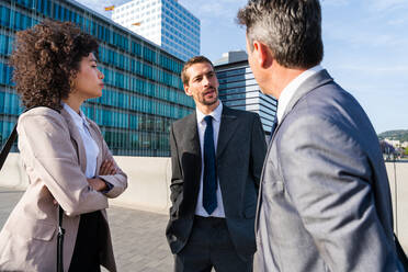 Multiracial group of business people bonding outdoors - International business corporate team wearing elegant suit meeting in a business park - DMDF00632