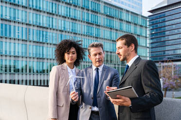 Multiracial group of business people bonding outdoors - International business corporate team wearing elegant suit meeting in a business park - DMDF00638