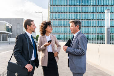 Multiracial group of business people bonding outdoors - International business corporate team wearing elegant suit meeting in a business park - DMDF00643