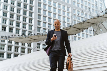 Young business man going to work in the morning passing by the financial street area of the city .Representation of a successful sales person reaching the top of the career. - DMDF00756