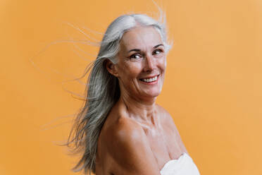 Bild einer schönen älteren Frau, die für eine Beauty-Fotosession posiert. Frau mittleren Alters auf einem farbigen Hintergrund. Konzept über Körperpositivität, Selbstwertgefühl und Körperakzeptanz - DMDF00779
