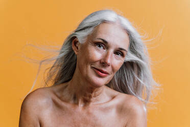 Image of a beautiful senior woman posing on a beauty photo session. Middle aged woman on a colored background. Concept about body positivity, self esteem and body acceptance - DMDF00780