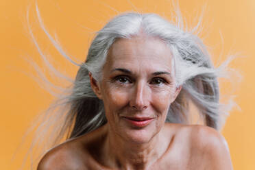Image of a beautiful senior woman posing on a beauty photo session. Middle aged woman on a colored background. Concept about body positivity, self esteem and body acceptance - DMDF00781
