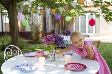 Lächelndes Mädchen deckt den Tisch für eine Geburtstagsfeier im Garten - SVKF01573