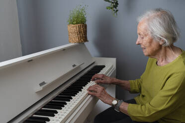 Senior woman playing piano at home - SVKF01577