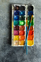Top view of palette of colorful bright used aquarelle paints on gray background - ADSF46235