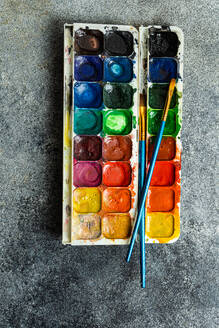 Top view of palette of colorful bright used aquarelle paints on gray background - ADSF46235