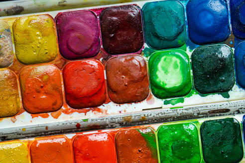 Top view of palette of colorful bright used aquarelle paints as abstract textured background - ADSF46236