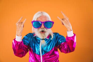 Senior man with eccentric look - 60 years old man having fun, portrait on colored background, concepts about youthful senior people and lifestyle - DMDF00925