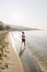 Woman running on coastline at beach - SIF00784