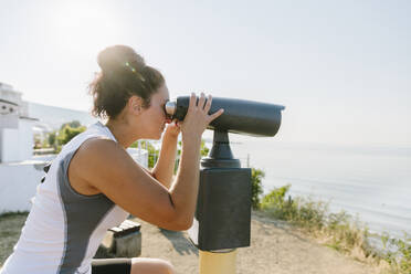 Woman looking through stationary binoculars on sunny day - SIF00792