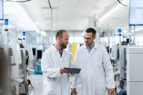 Two colleagues looking at digital tablet at work meeting in electronics factory - DIGF20163