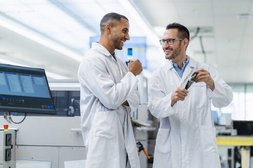 Two smiling colleagues in electronics factory having meeting holding motherboard - DIGF20168