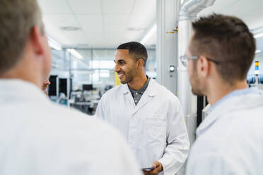 Ein Team fachkundiger Elektrotechniker in Laborkitteln bespricht sich in einer Elektronikfabrik - DIGF20195