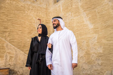 Arabian couple with traditional emirates dress dating outdoors - Happy middle-eastern couple having fun - DMDF01014