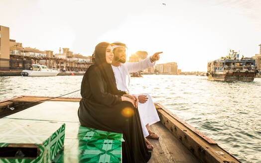 Arabian married couple visiting Dubai on abra boat - Two people on traditional boat at Dubai creek - DMDF01026