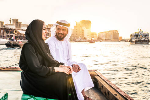 Arabian married couple visiting Dubai on abra boat - Two people on traditional boat at Dubai creek - DMDF01027